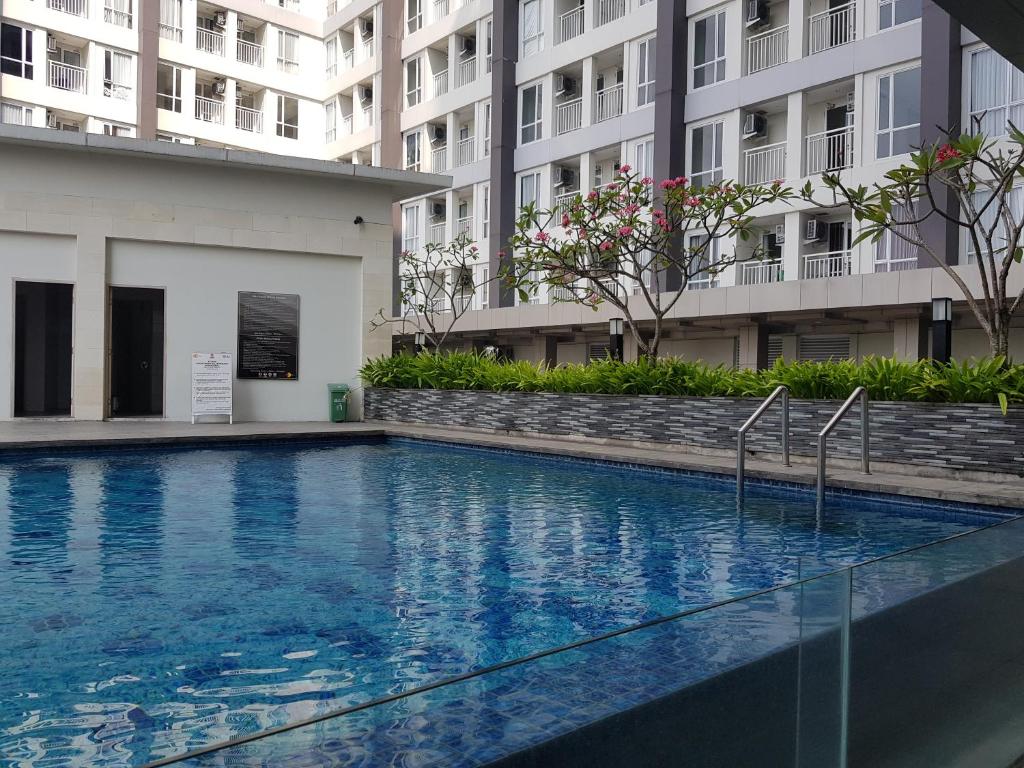 日惹Apartemen Taman Melati Sinduadi 60的一座大型游泳池,位于部分建筑前