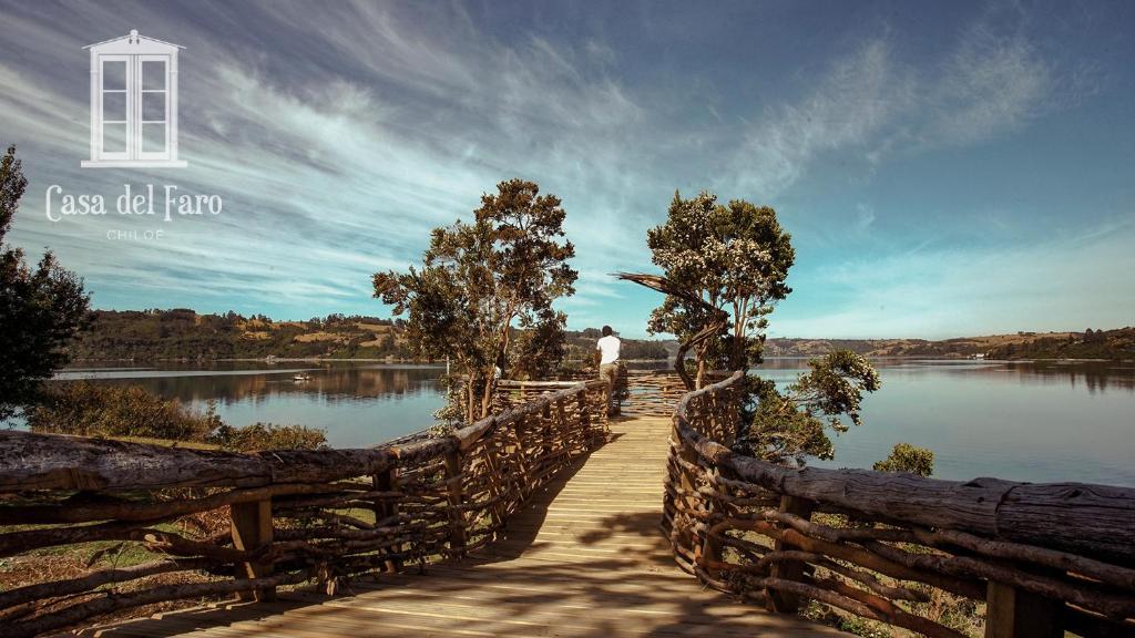 卡斯特鲁Casa del Faro Chiloé的站在湖上木桥上的男人