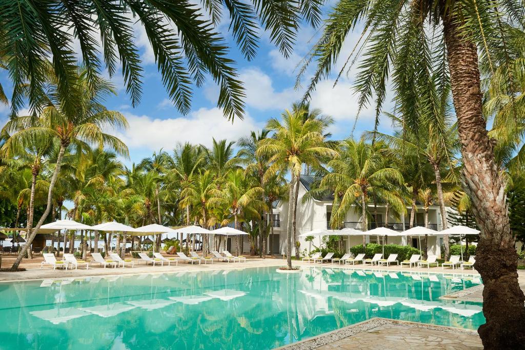巴拉克拉瓦旅人蕉风姿酒店的度假村的游泳池拥有棕榈树和遮阳伞