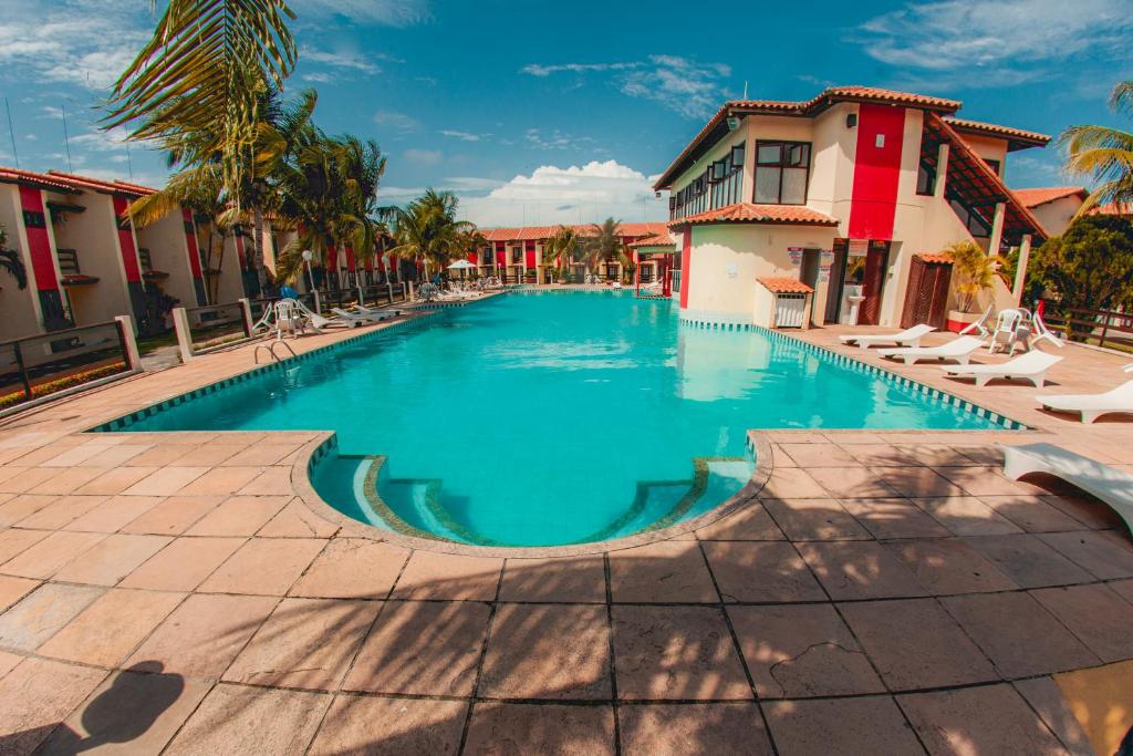 塞古罗港Casa Duplex 3 Suítes em Condomínio的棕榈树和建筑度假村内的游泳池