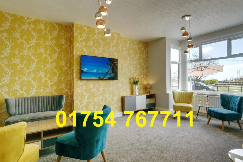 斯凯格内斯Palm Court, Seafront Accommodation的客厅配有沙发、椅子和电视