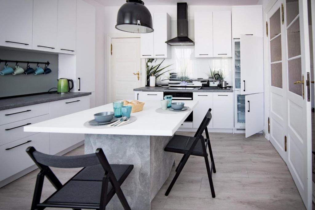 乌斯特卡Apartament Monopoli的厨房配有白色橱柜和一个带椅子的白色岛屿