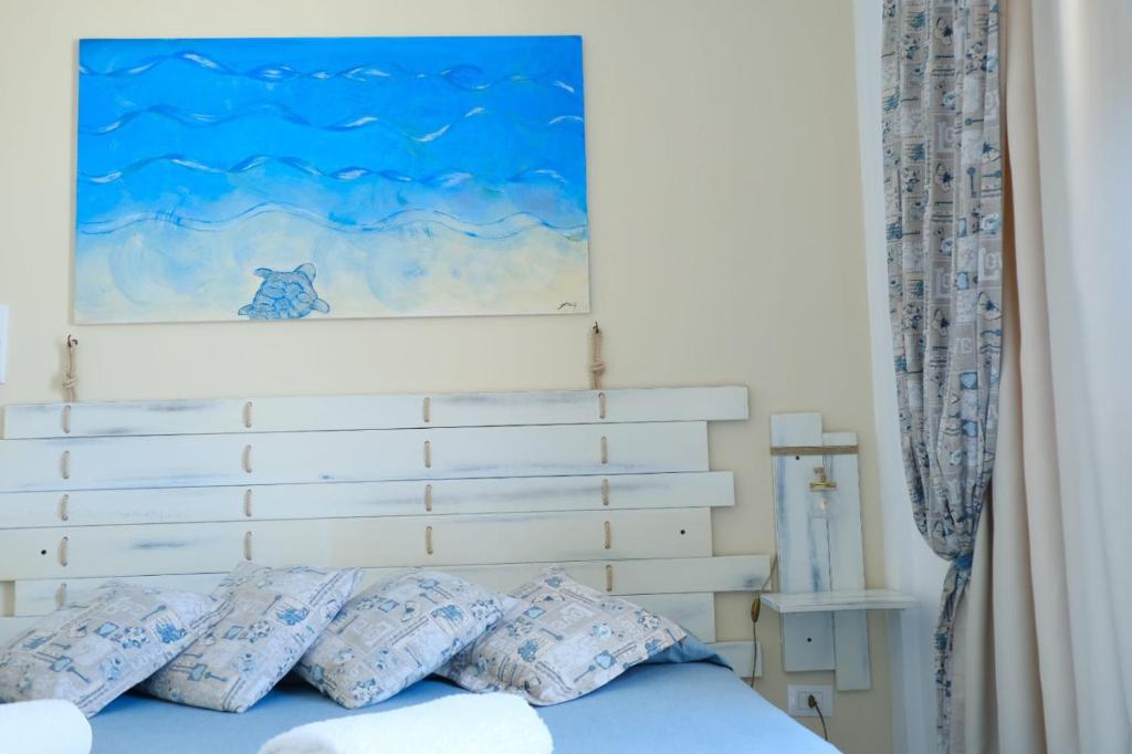兰佩杜萨B&B Una favola di mare的一张带蓝色枕头的床和上面的绘画