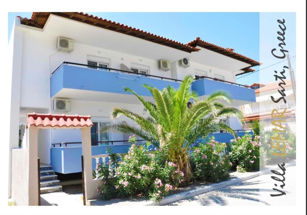 萨尔蒂Villa Lemar的一座蓝白色的建筑,种植了棕榈树和植物