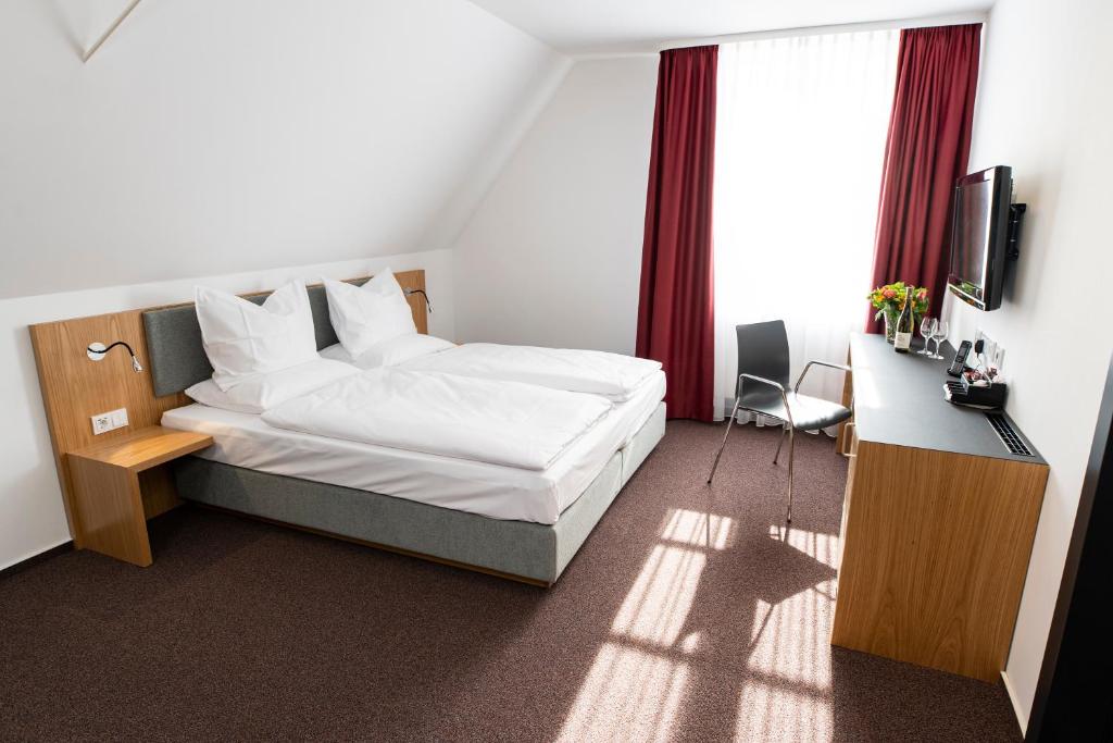 埃尔特维勒Hotel Kloster Eberbach的一间卧室配有一张床、一张书桌和一台电视