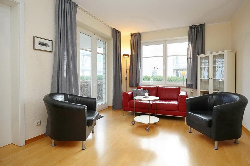 博尔滕哈根Dünenblick Wohnung 35的客厅配有红色的沙发和椅子