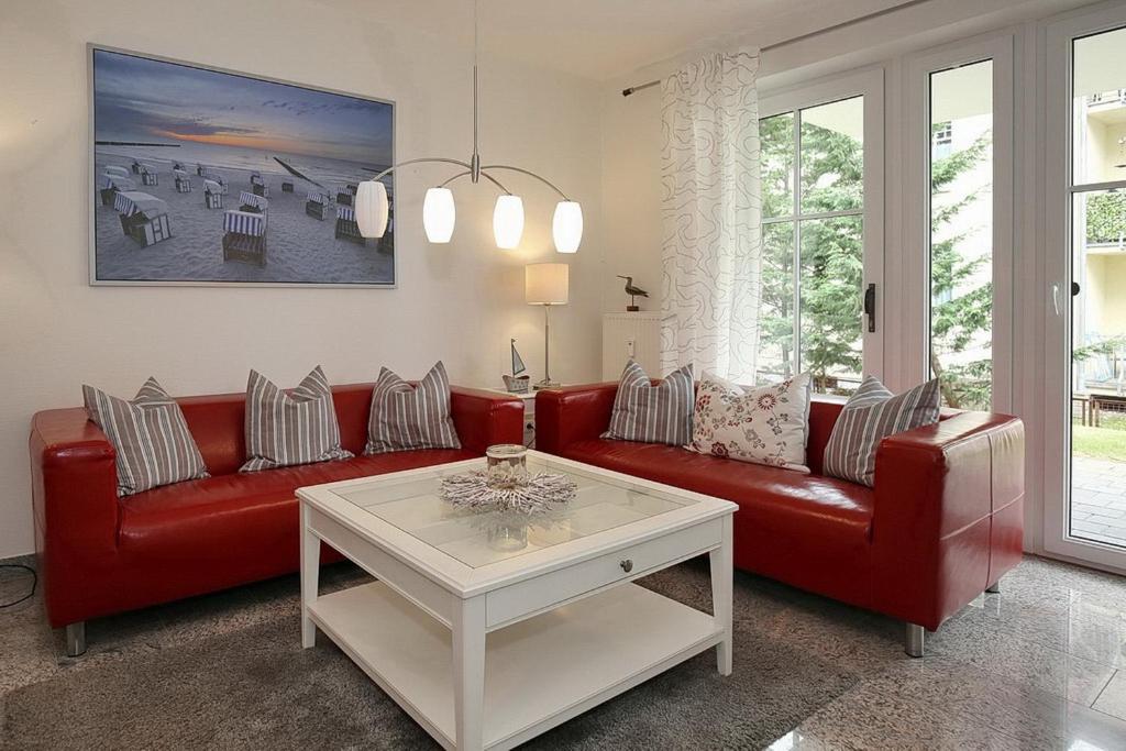 博尔滕哈根Strandvilla Niklot Wohnung 02的客厅配有红色皮革沙发和桌子