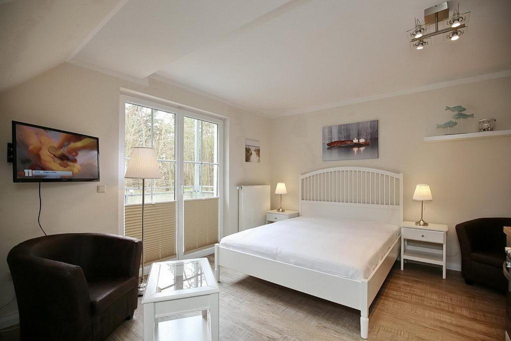 博尔滕哈根Strandvilla Krabbe Wohnung 11的卧室配有白色的床和椅子