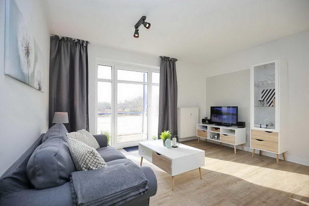 博尔滕哈根Haffblick Wohnung 42的客厅配有蓝色的沙发和电视