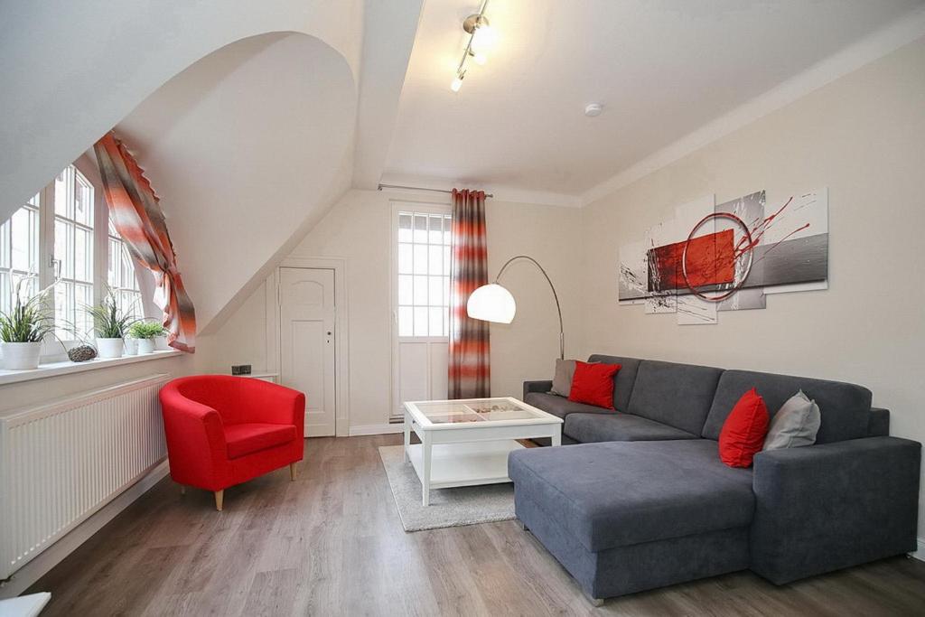 博尔滕哈根Strandvilla Krabbe Wohnung 05的带沙发和红色椅子的客厅