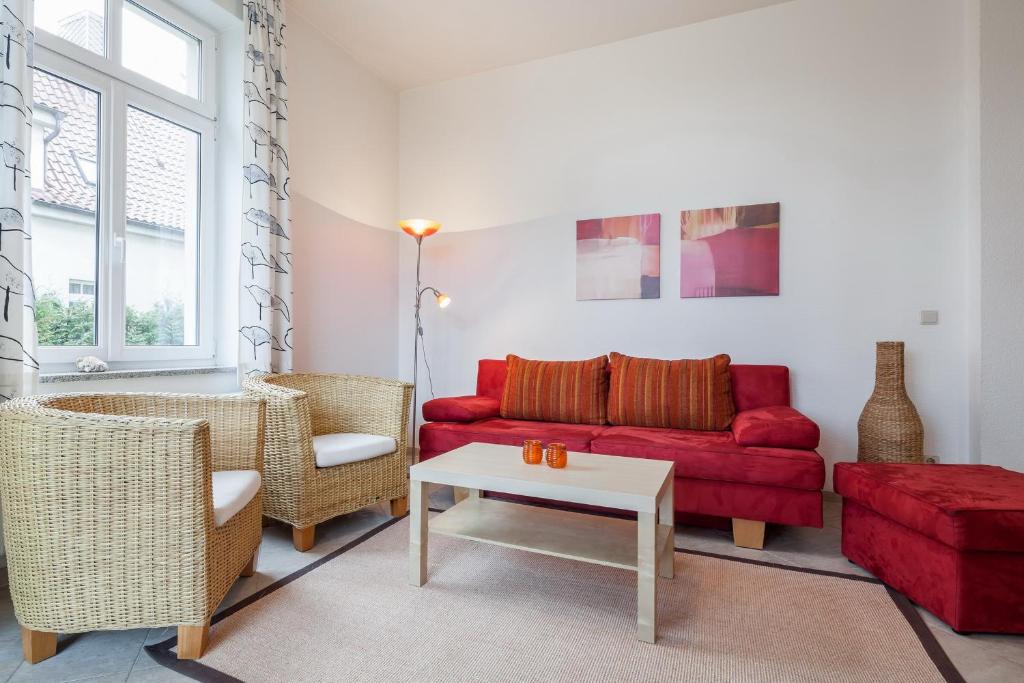 博尔滕哈根Villa Triton Wohnung 02的客厅配有红色的沙发和椅子
