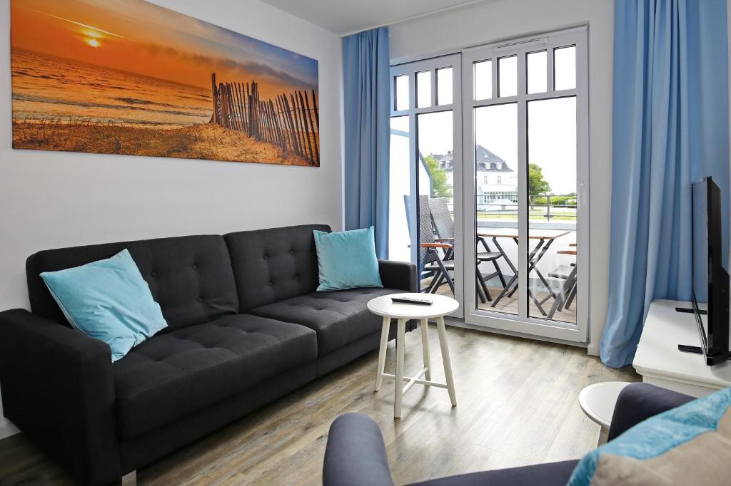 海利根达姆Linden-Palais Wohnung 31的一间带黑色沙发的客厅和一个阳台