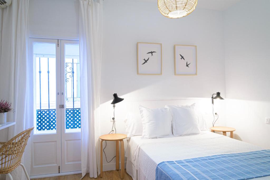 塔里法卡尔萨达旅馆的白色卧室配有一张带蓝色毯子的床