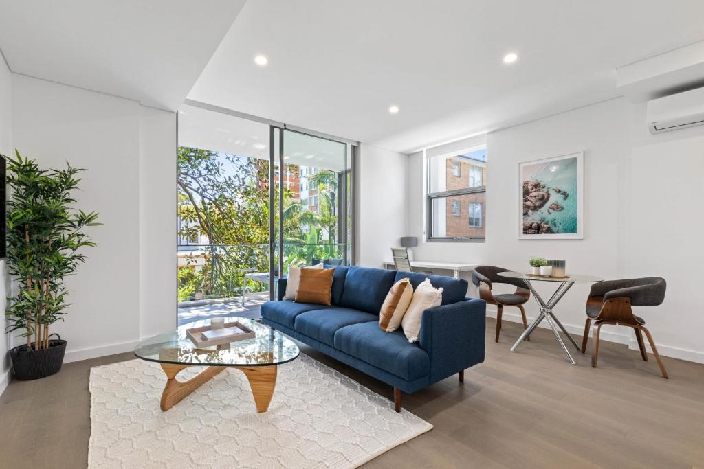 悉尼Azure Apartments by Urban Rest的客厅配有蓝色的沙发和桌子