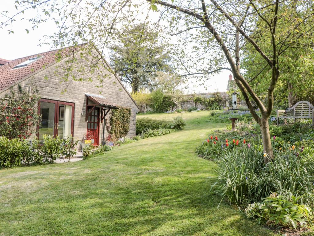 Buckland St MaryFlintstones的一座带房子的院子和一座鲜花盛开的花园