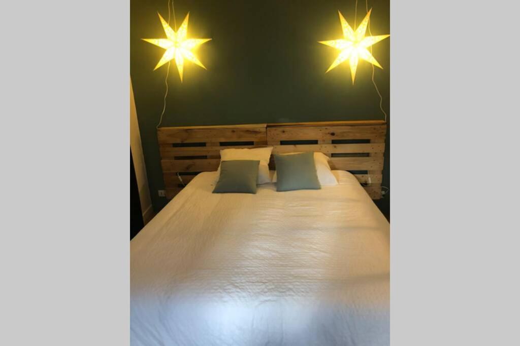 AumontLa tête dans les étoiles的一间卧室配有带两个枕头和灯的床