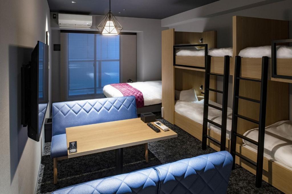 札幌ALPHABED INN Sapporo Odori Park的客房设有双层床、桌子和沙发。