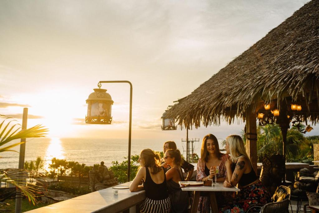 坎古Hotel Tugu Bali - CHSE Certified的一群坐在桌子上,背景是海洋的女人