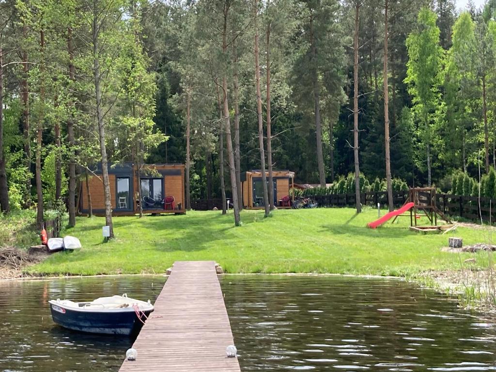 MakosiejeMakosieje Resort-komfortowy domek 15m od jeziora,widok na jezioro,ogrzewanie,wi-fi的公园旁边的水面上的小船码头