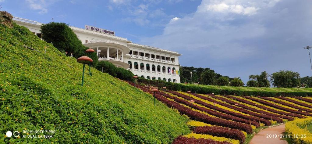 BelagulaRoyal Orchid Brindavan Garden Mysore的一座大建筑,前面设有花园