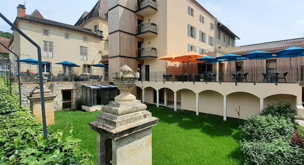 圣西普里安Hotel-Restaurant des Augustins - Cosy Places by CC - Proche Sarlat的一座带庭院的建筑,庭院内配有桌子和遮阳伞