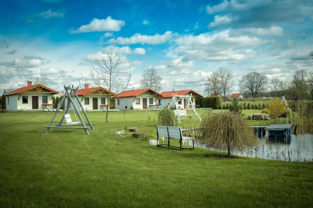 TałtyNatalia Rest domki & camp的一个带长凳、池塘和房屋的公园