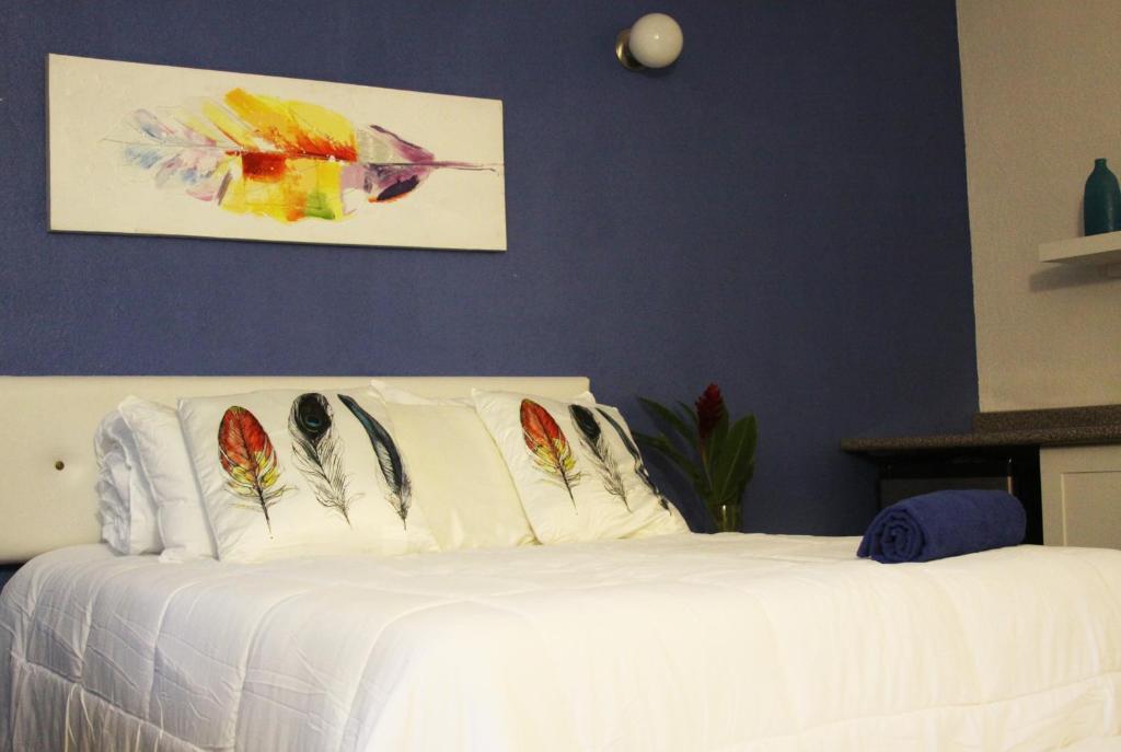 危地马拉Super Ubicacion的卧室配有带羽毛枕头的白色床。