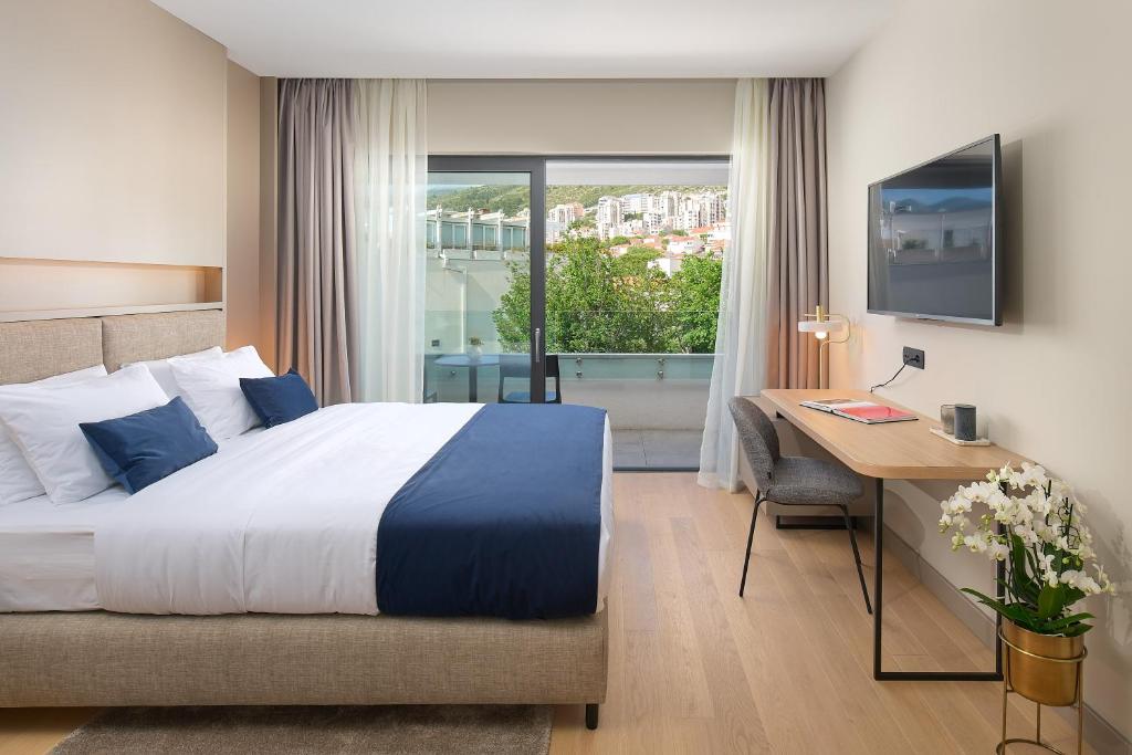 杜布罗夫尼克Boutique Hotel Porto的配有一张床、一张书桌和一扇窗户的酒店客房