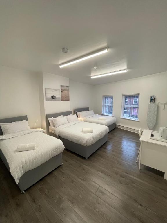利物浦County serviced accommodation的客房设有两张床和一张带水槽的书桌。