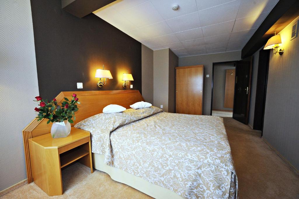 贝乌哈图夫斯波特酒店的一间卧室配有一张床和一张鲜花桌子