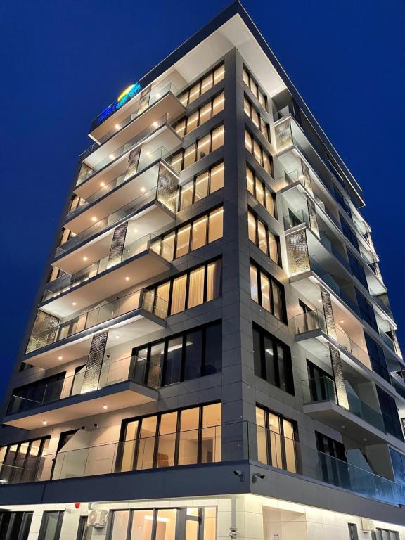 马马亚Bel Air Apartments Mamaia Nord的一座高大的建筑,晚上有很多窗户