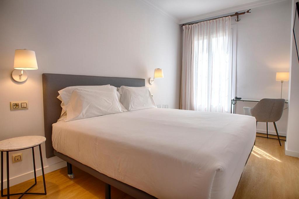 马拉加Sercotel Tribuna Málaga的卧室配有一张白色大床和一把椅子