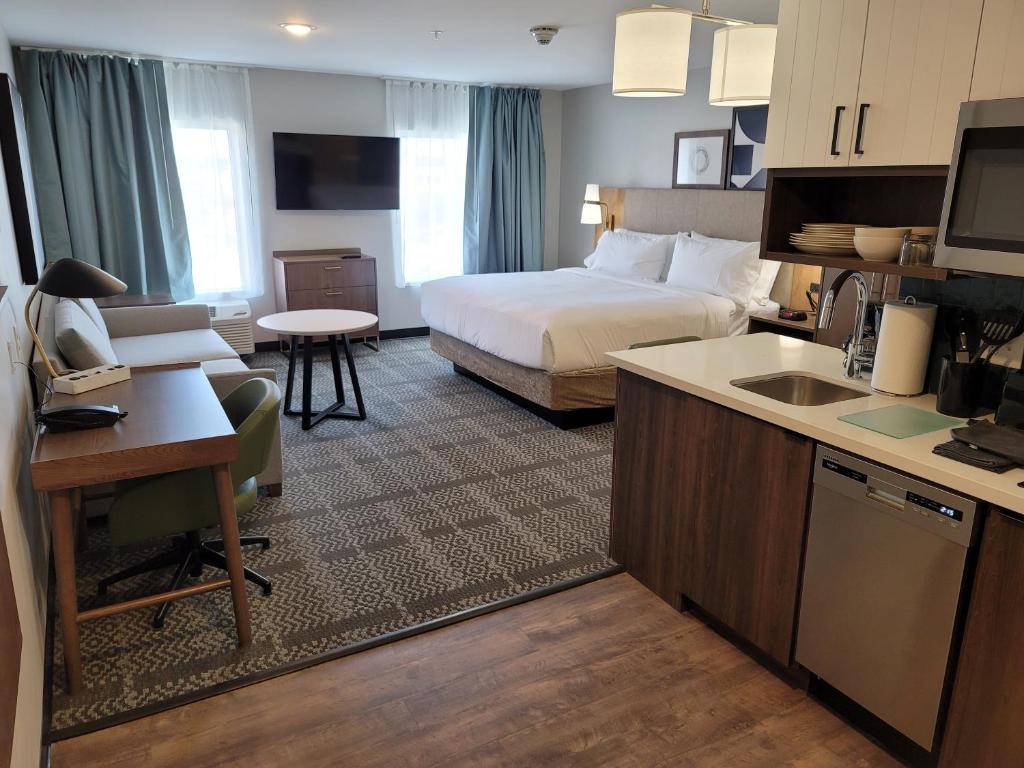 路易斯威尔Staybridge Suites - Louisville - Expo Center, an IHG Hotel的酒店客房配有一张床、一张书桌和一间厨房。