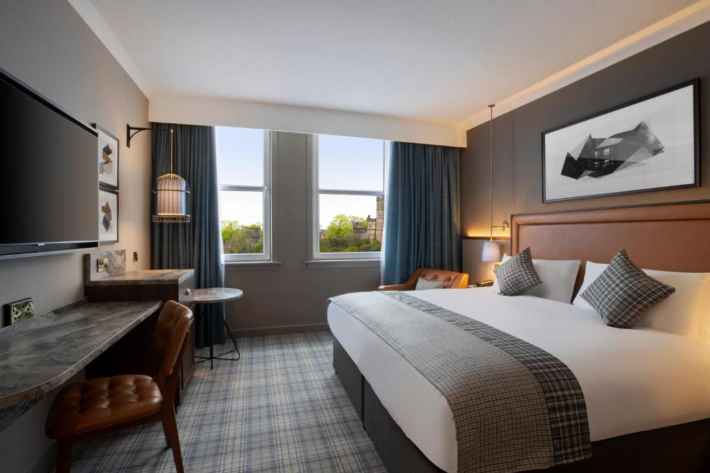 爱丁堡Leonardo Royal Hotel Edinburgh的酒店客房设有一张大床和一张书桌。