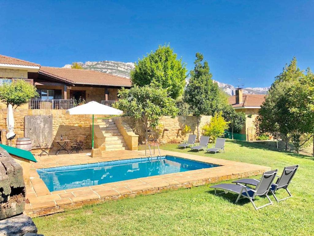 萨马涅戈SagastiEnea Villa con Piscina y Tenis en la Rioja的庭院内的游泳池配有椅子和遮阳伞