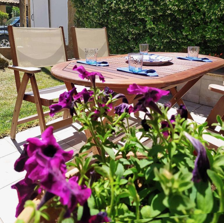 Skála NikítaSeaside Villa Clio的一张木桌和椅子以及紫色的鲜花