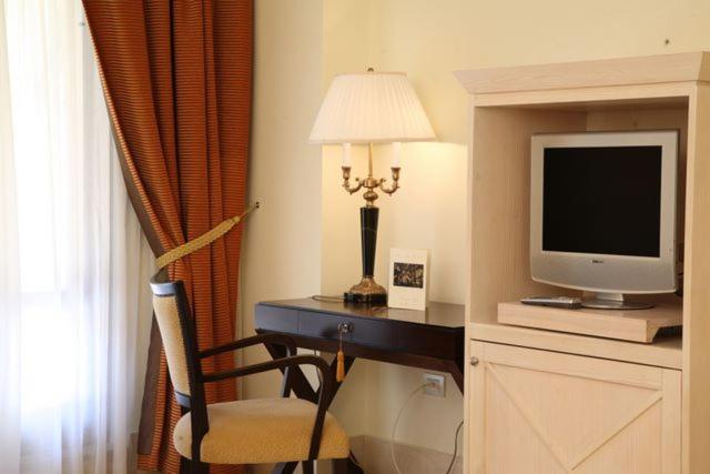 克罗托内Hotel Lido degli Scogli的酒店客房配有书桌、电视和台灯
