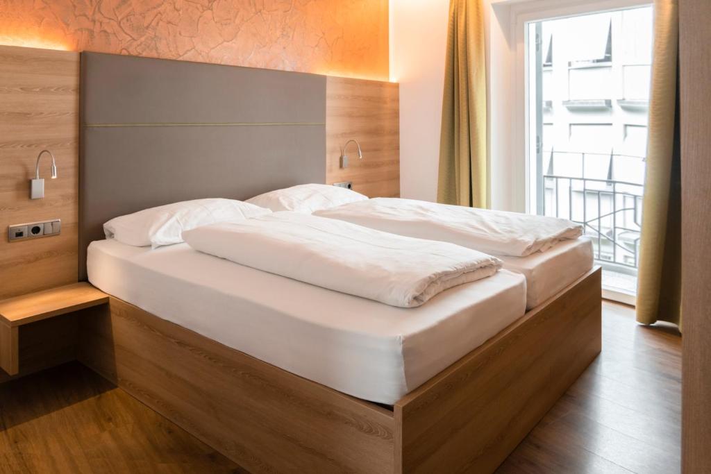 博尔扎诺Feichter Hotel & Bistro的一张大床,位于带大窗户的房间里