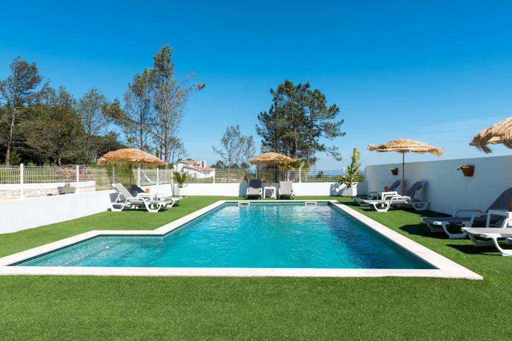 菲盖拉-达福什Quinta Bogesi的庭院内的游泳池,配有椅子和遮阳伞