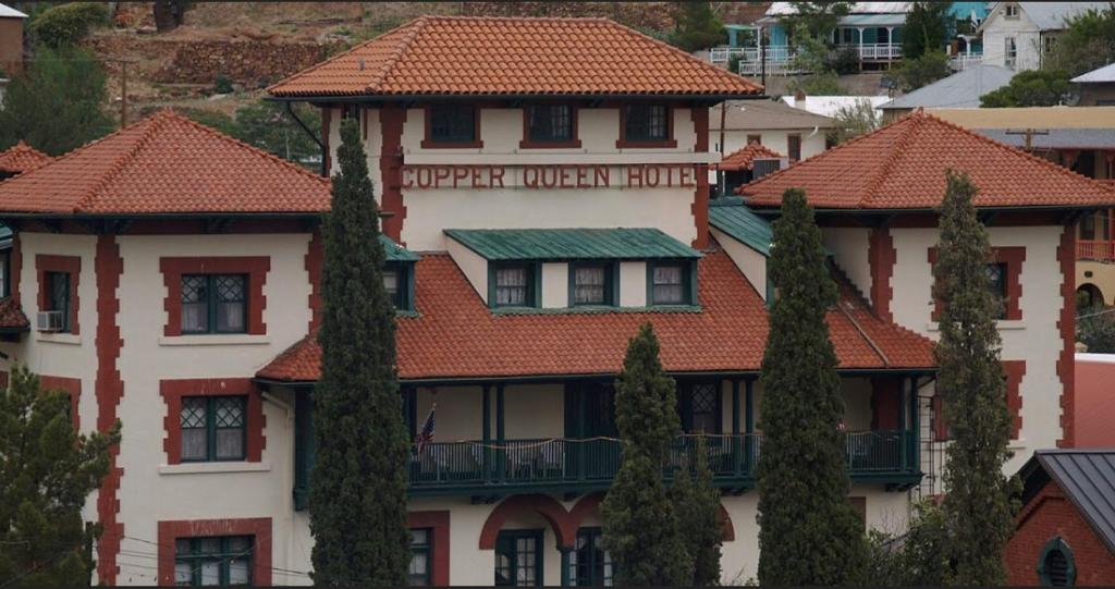 比斯比青铜皇后大酒店的一座有红瓦屋顶和树木的建筑