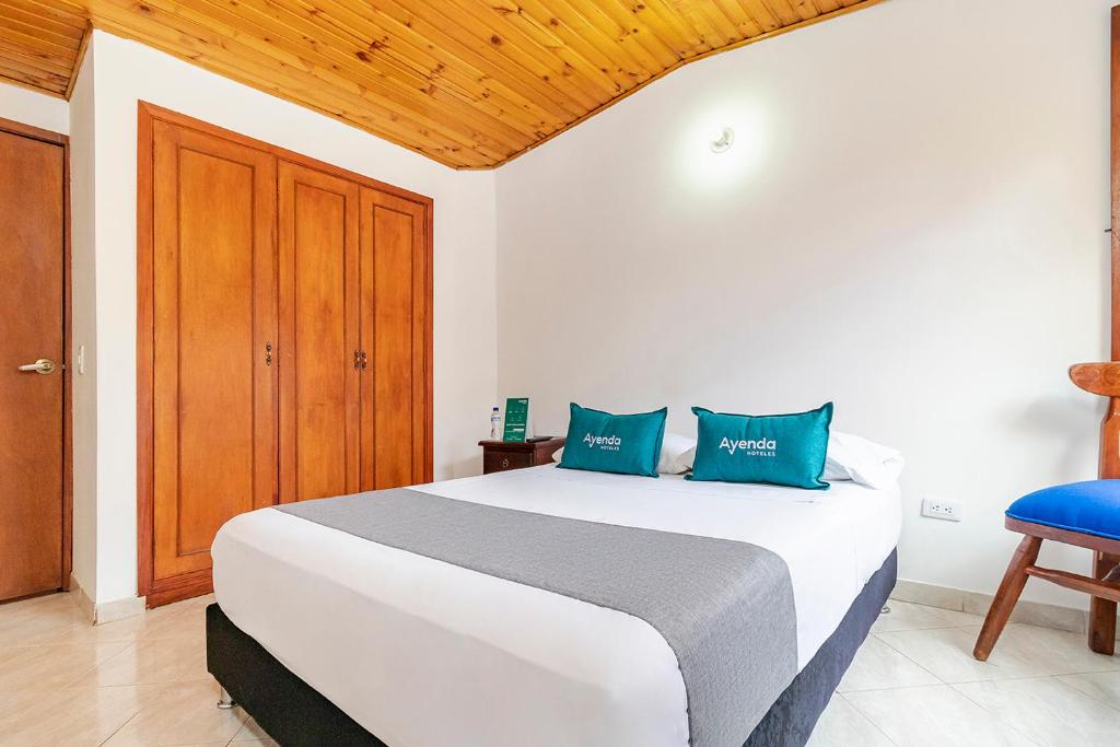 奇亚Ayenda Hotel Casona Santa Rosa的卧室配有带蓝色枕头的大型白色床
