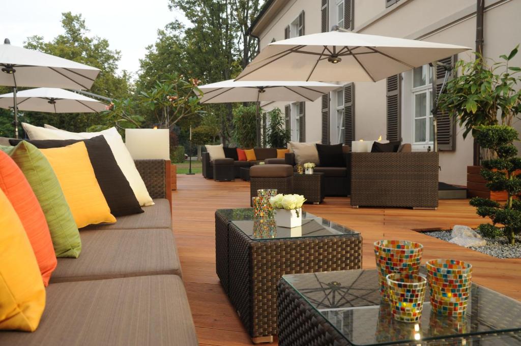 莱茵河畔路德维希港勒内博恩酒店的一个带沙发和桌子及遮阳伞的庭院
