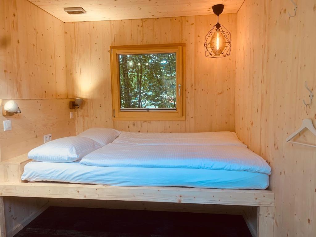 因特拉肯RiverLodge TCS Training & Freizeit AG的木制客房的一张床位,设有窗户