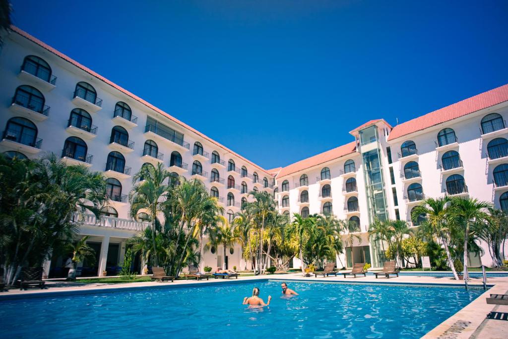 埃斯孔迪多港Hotel Caracol Plaza的两人在酒店前的游泳池