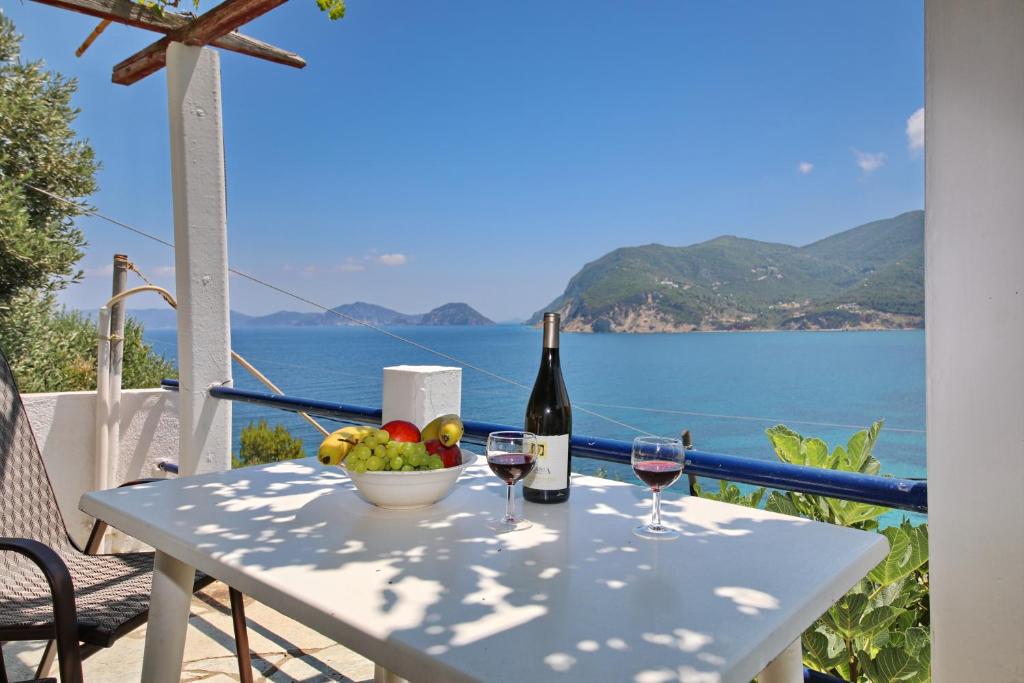 斯科派洛斯ΣΕΡΓΙΑΝΙ ΣΚΟΠΕΛΟΥ的一张桌子,上面放着两杯葡萄酒和一碗水果
