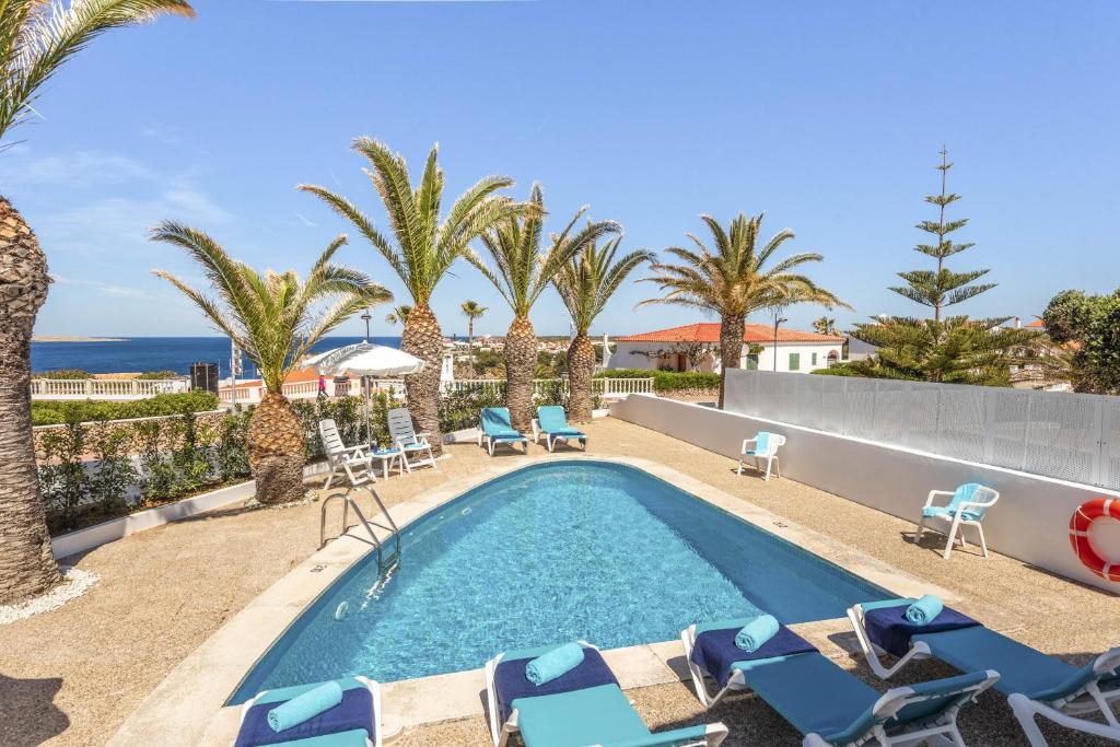 阿雷纳尔登卡斯特尔Villa Lali的一个带椅子和棕榈树的游泳池以及大海