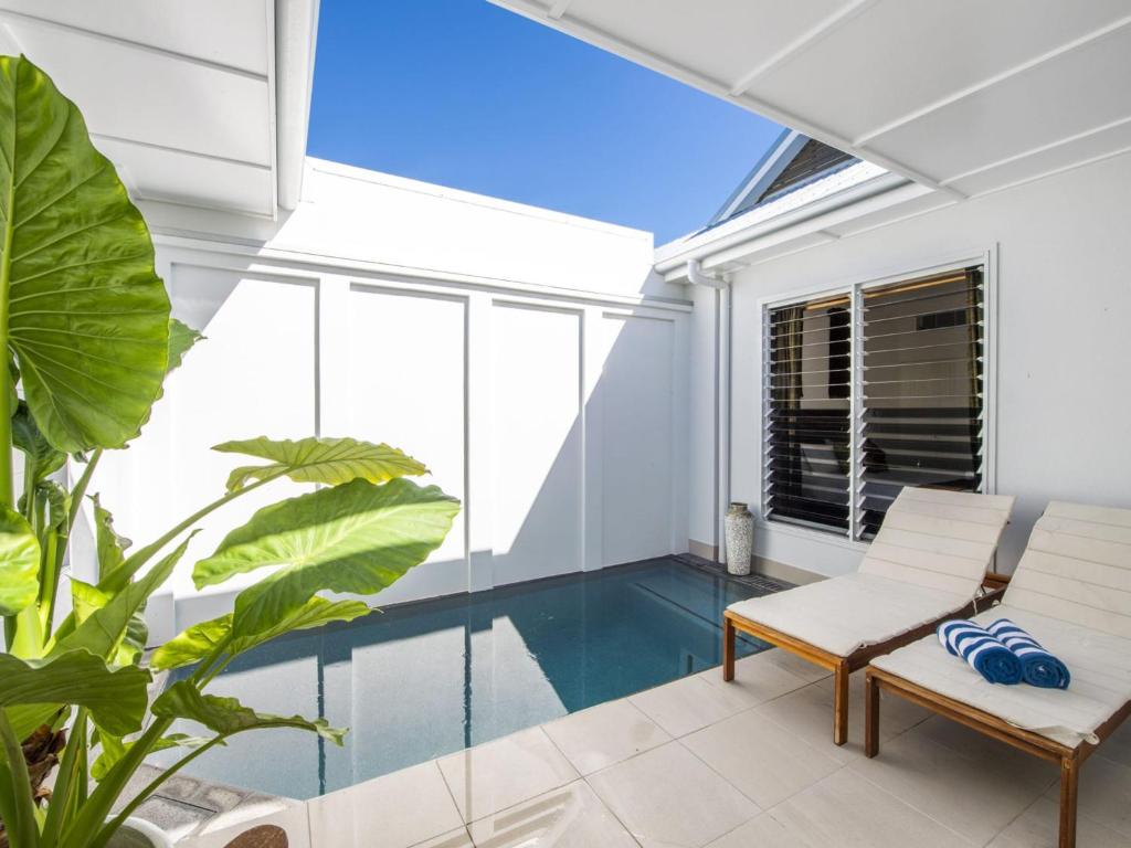 Picnic BayReflections Emerald Villa 1的一座室内泳池,室内装饰有白色的家具和植物