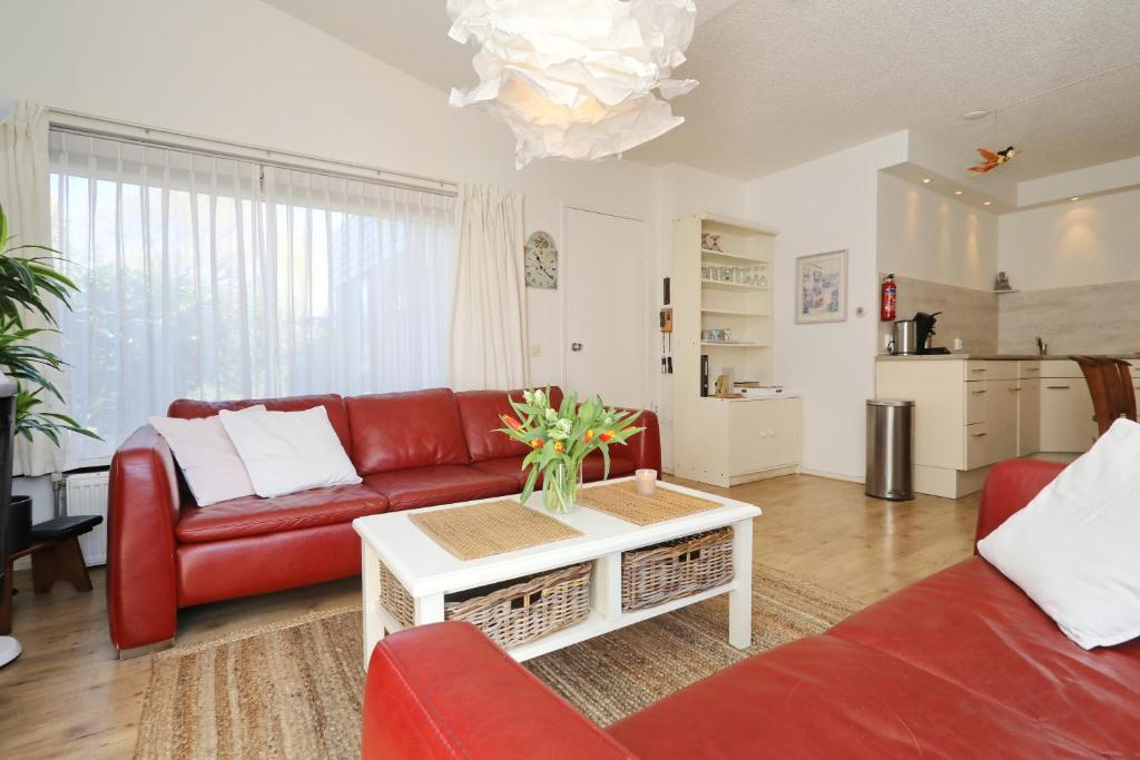 诺德克豪特Holiday home de Zeester的客厅配有红色的沙发和桌子