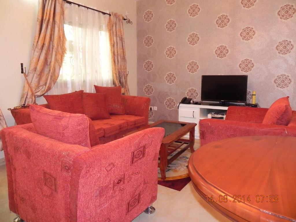 雅温得Résidence La ROSÉE的客厅配有红色椅子、桌子和电视