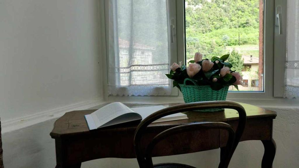 PadergnoneCasa alla Cantinota Padergnone Ospitar的一张桌子,上面有一本书和花瓶